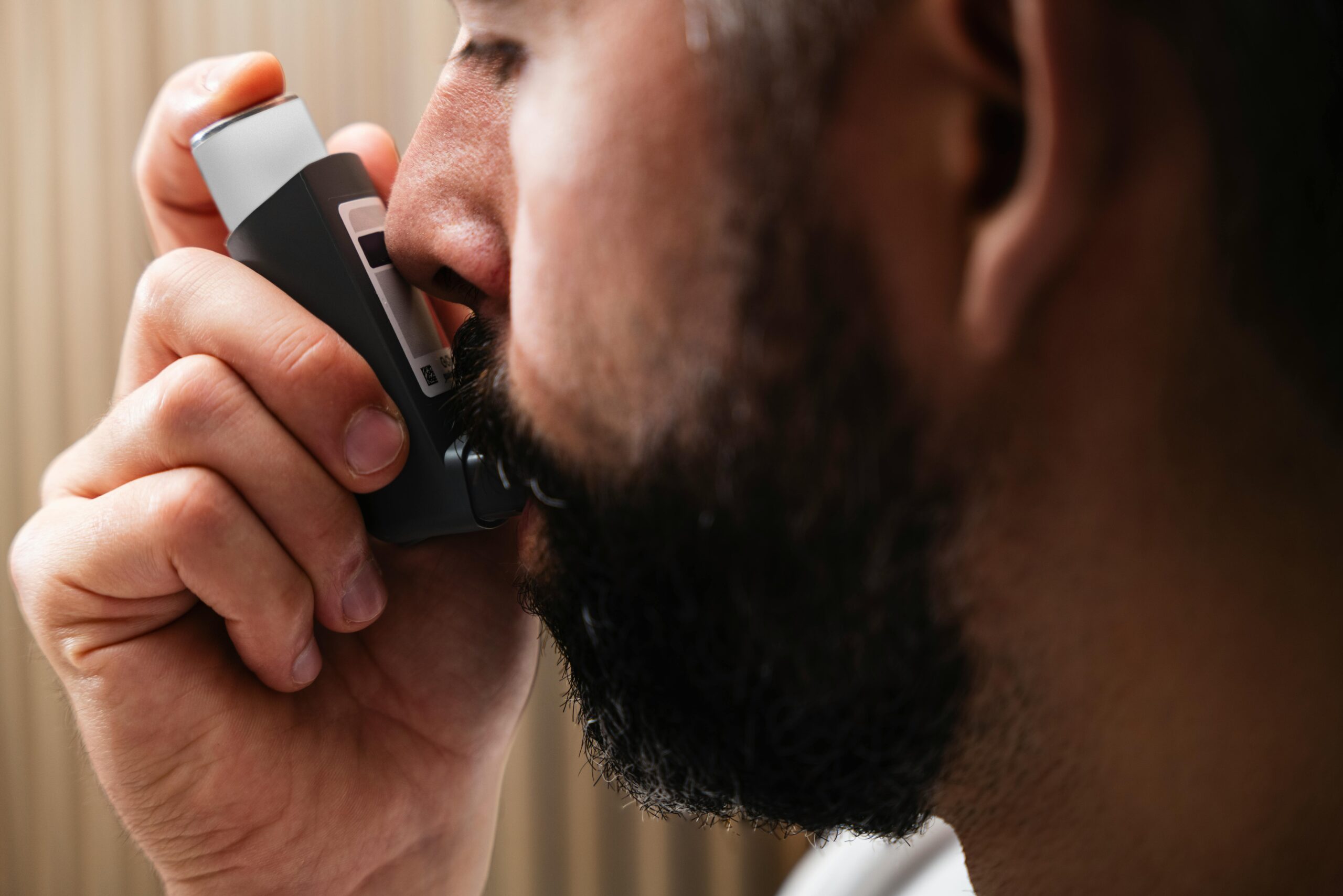 A close-up image of a man using an inhaler, highlighting respiratory health concepts.