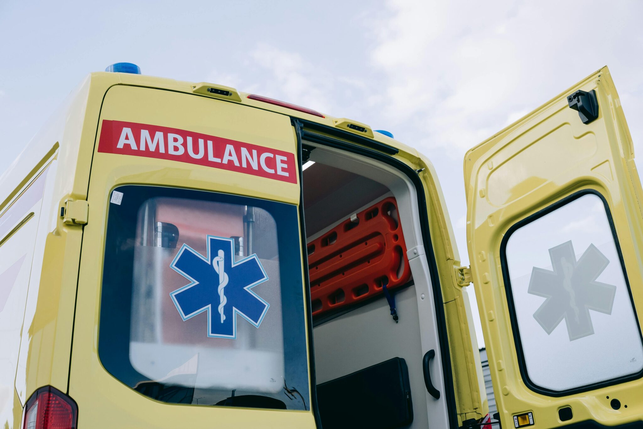 Yellow ambulance with open doors displaying medical interior equipment, emphasizing emergency response.